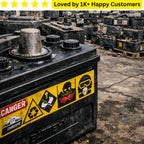 Used car battery with warning labels in an outdoor setting, surrounded by other batteries. Is your battery labels branding peeling off before the first charge is even finished?