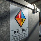 Metal container with hazardous material label indicating acid and reactive substances. SANS-Compliant Battery Labels: Self-Adhesive from 1XA4🔋⚡