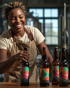 Person in a brewery setting with beer bottles and a smile